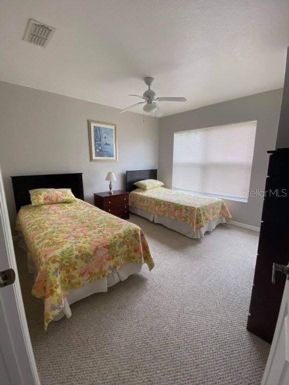 carpeted bedroom with visible vents, baseboards, and ceiling fan