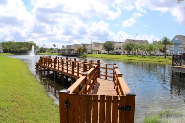 view of dock featuring a yard, a residential view, and a water view
