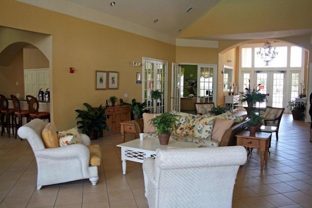 living room with a chandelier, arched walkways, high vaulted ceiling, and light tile patterned floors