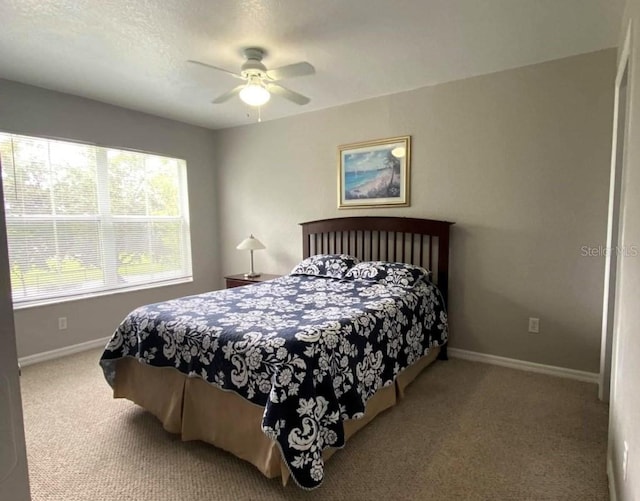 carpeted bedroom with ceiling fan and baseboards