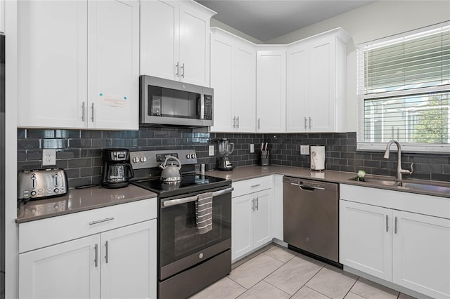 kitchen with light tile patterned floors, a sink, backsplash, and appliances with stainless steel finishes