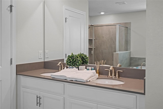 full bathroom featuring a shower stall, double vanity, a sink, and visible vents