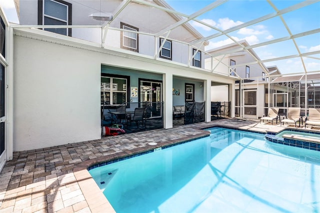 view of swimming pool with a pool with connected hot tub, glass enclosure, and a patio