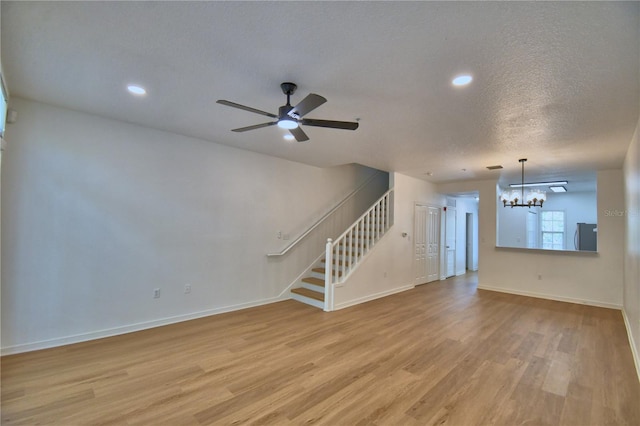 660 Celebration Ave Unit 240, Kissimmee, FL 34747 - unfurnished living room with stairs, ceiling fan with notable chandelier, light wood-style floors, baseboards, and recessed lighting