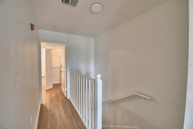 660 Celebration Ave Unit 240, Kissimmee, FL 34747 - hallway with wood finished floors, visible vents, an upstairs landing, baseboards, and a textured ceiling