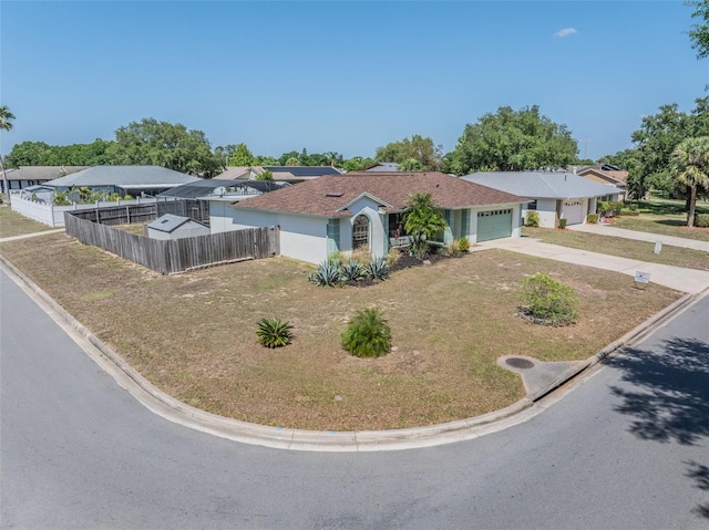view of front facade with concrete driveway, a front lawn, fence, and an attached garage