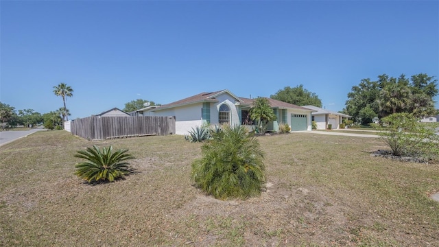 view of front of home with a front yard, a garage, concrete driveway, fence, and stucco siding