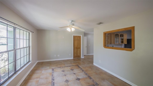 unfurnished room with light tile patterned floors, baseboards, a ceiling fan, and visible vents