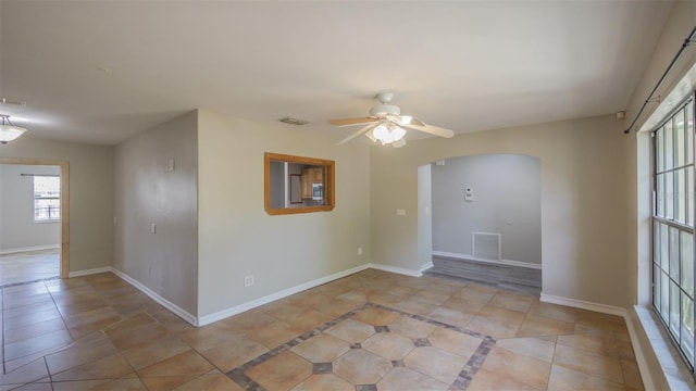 unfurnished room featuring arched walkways, baseboards, a ceiling fan, and visible vents