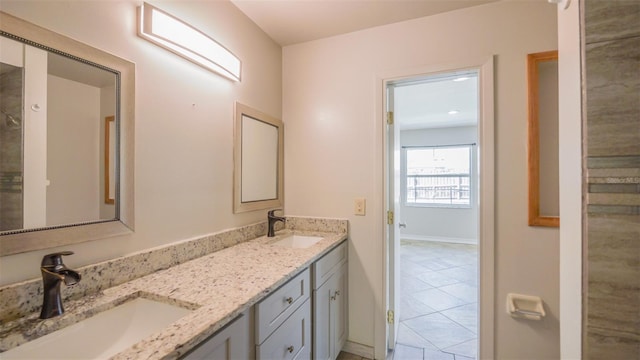 full bathroom featuring a sink, baseboards, double vanity, and tile patterned flooring