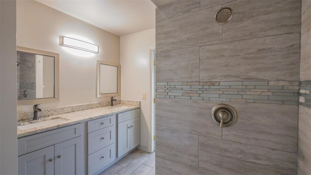 bathroom with a sink, tiled shower, and double vanity