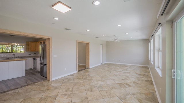 unfurnished living room with baseboards, recessed lighting, visible vents, ceiling fan, and a sink