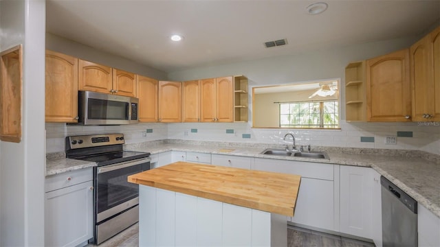 kitchen featuring a sink, visible vents, open shelves, and stainless steel appliances