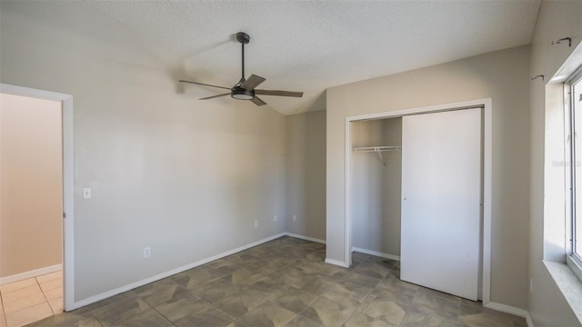 unfurnished bedroom featuring a closet, baseboards, ceiling fan, a textured ceiling, and lofted ceiling