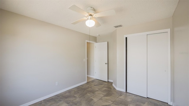 unfurnished bedroom featuring a closet, baseboards, a textured ceiling, visible vents, and ceiling fan