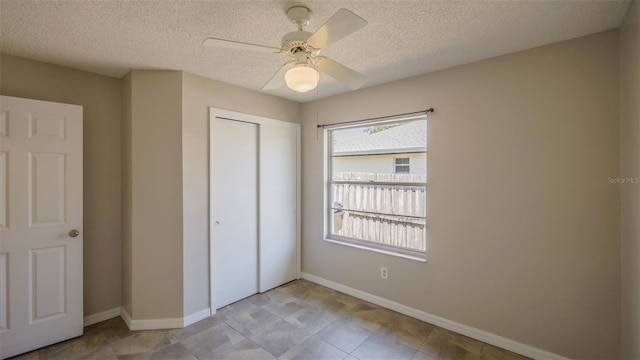 unfurnished bedroom featuring a textured ceiling, a closet, baseboards, and a ceiling fan