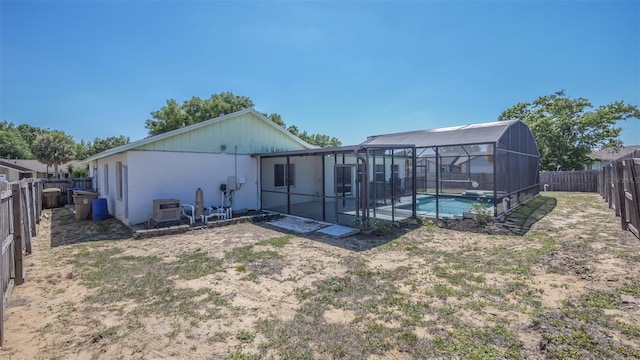 back of house featuring a lanai, a fenced backyard, and a fenced in pool