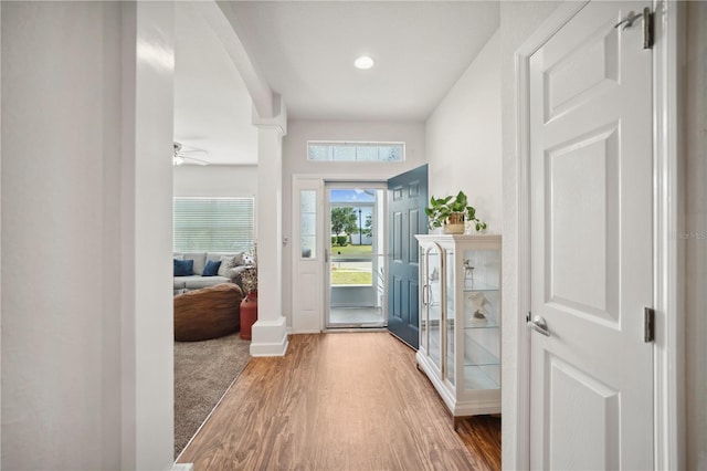 doorway with a ceiling fan, wood finished floors, baseboards, ornate columns, and recessed lighting