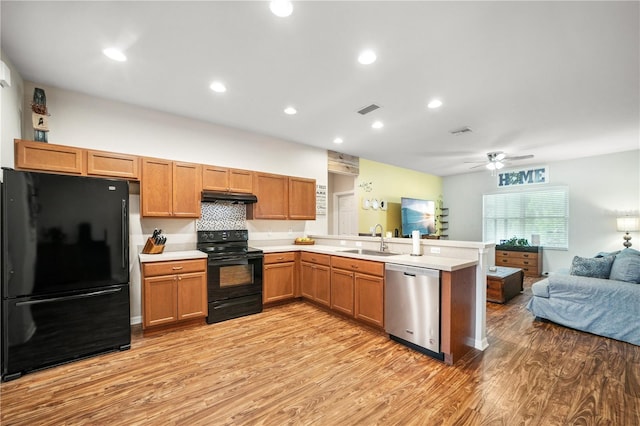 kitchen featuring a peninsula, open floor plan, under cabinet range hood, a sink, and black appliances