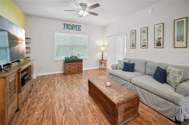 living room featuring baseboards, a ceiling fan, and wood finished floors
