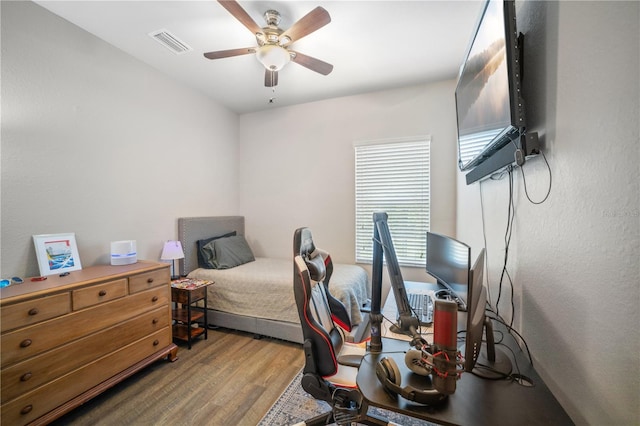 bedroom featuring a ceiling fan, wood finished floors, and visible vents