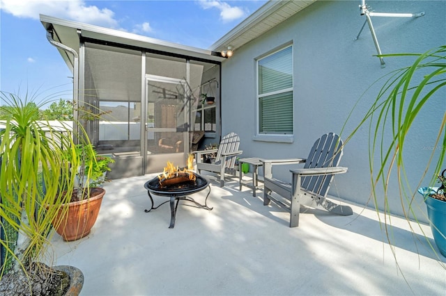 view of patio / terrace featuring a sunroom and a fire pit