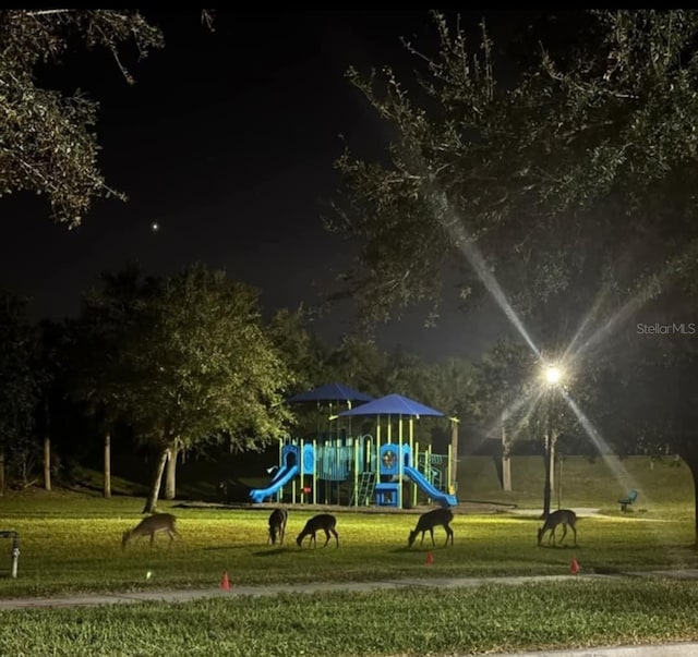 playground at night featuring a lawn and playground community