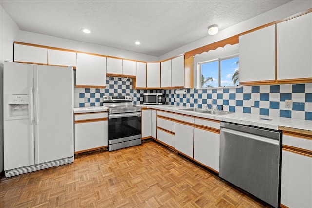 kitchen featuring a sink, decorative backsplash, white cabinets, appliances with stainless steel finishes, and recessed lighting