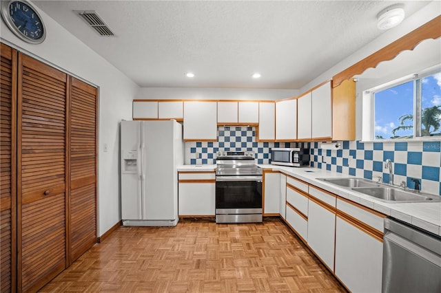 kitchen featuring visible vents, appliances with stainless steel finishes, white cabinetry, and a sink