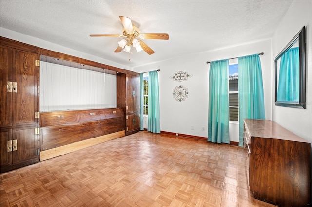 empty room with a textured ceiling, baseboards, and ceiling fan