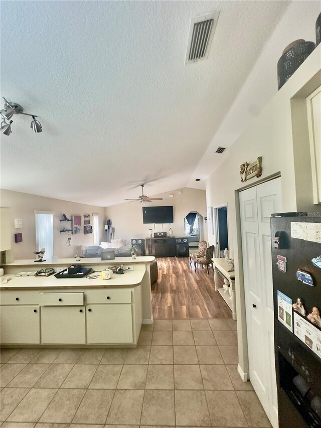kitchen with light tile patterned floors, a textured ceiling, light countertops, cream cabinetry, and visible vents