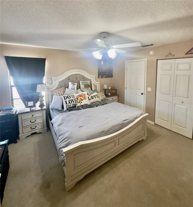 bedroom with light carpet, visible vents, a textured ceiling, and a ceiling fan