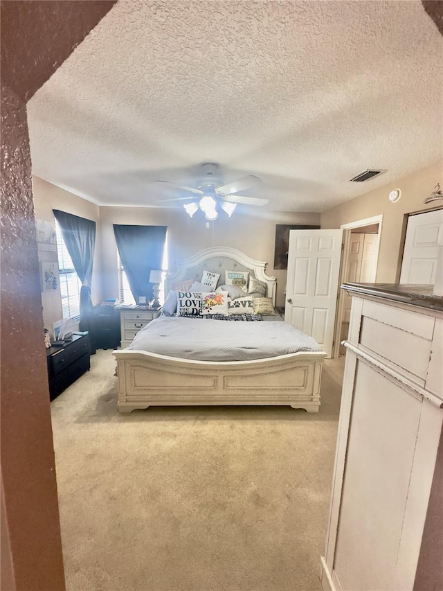 bedroom with visible vents, a textured ceiling, a ceiling fan, and carpet floors