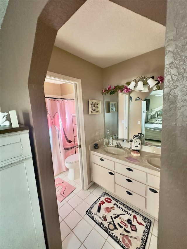 ensuite bathroom with a sink, toilet, double vanity, connected bathroom, and tile patterned flooring