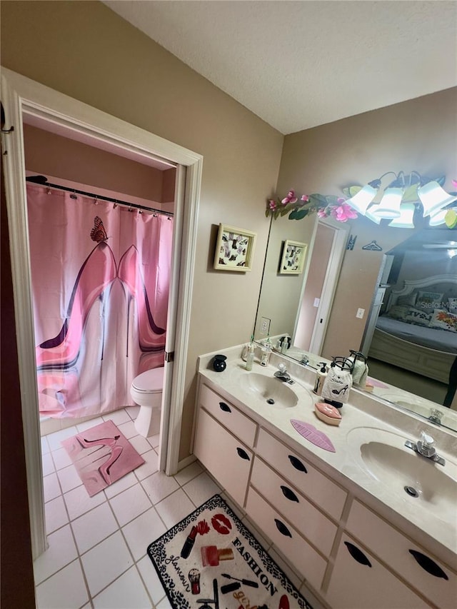full bathroom featuring toilet, tile patterned floors, double vanity, and a sink