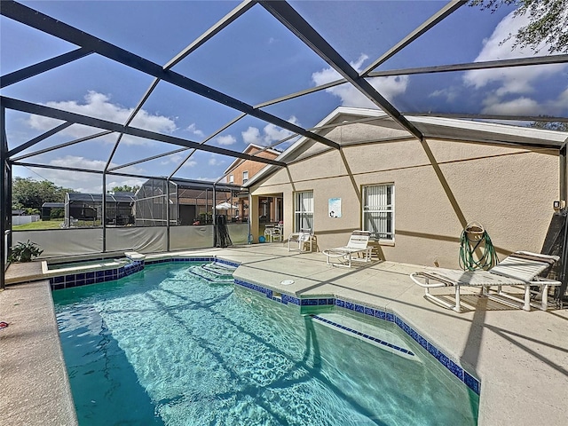 view of pool featuring glass enclosure, a patio area, and a pool with connected hot tub