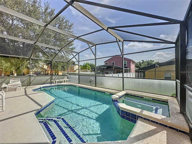 view of swimming pool featuring glass enclosure, a pool with connected hot tub, and a patio