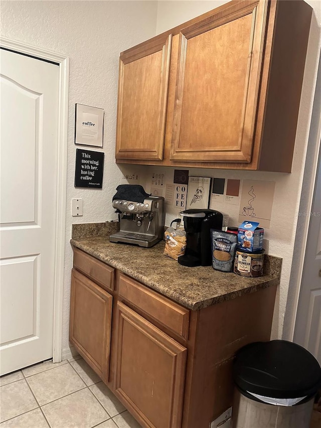 6141 Metrowest Blvd Unit 303, Orlando, FL 32835 - kitchen featuring light tile patterned floors, brown cabinetry, dark countertops, and a textured wall