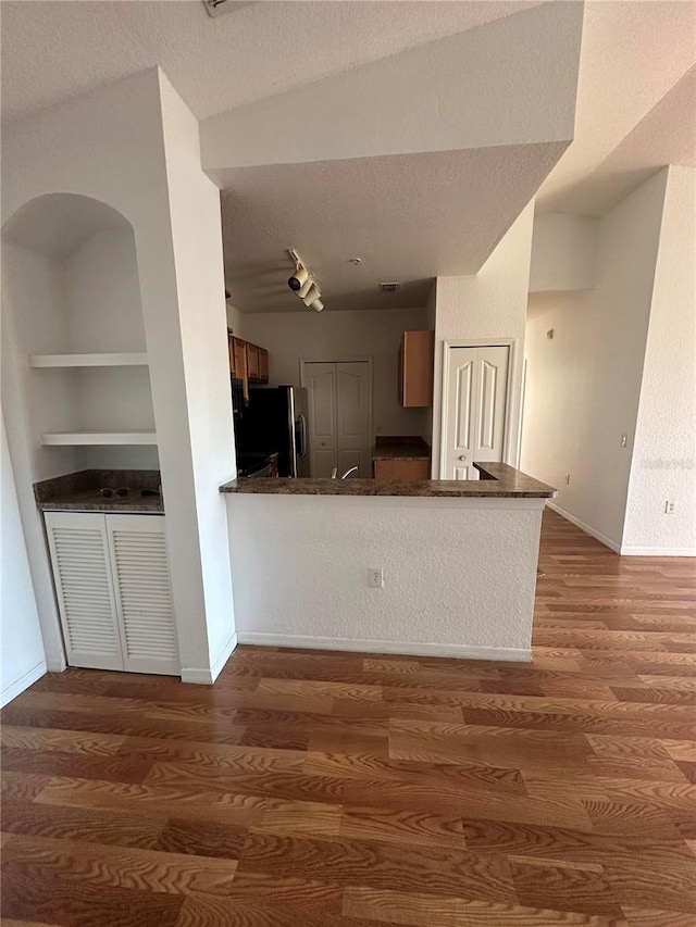 6141 Metrowest Blvd Unit 303, Orlando, FL 32835 - kitchen with freestanding refrigerator, dark countertops, wood finished floors, a textured ceiling, and built in shelves