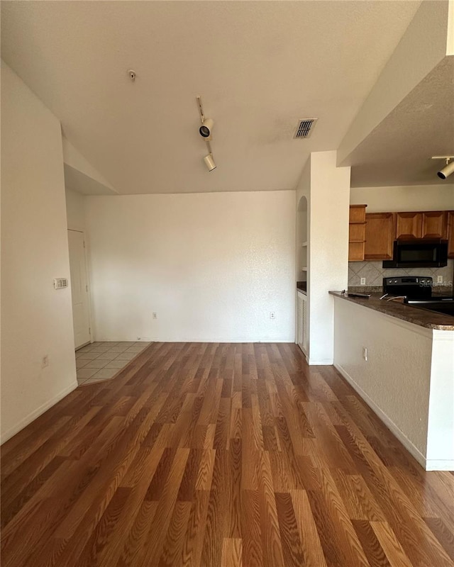 6141 Metrowest Blvd Unit 303, Orlando, FL 32835 - kitchen with black appliances, brown cabinets, dark countertops, and wood finished floors