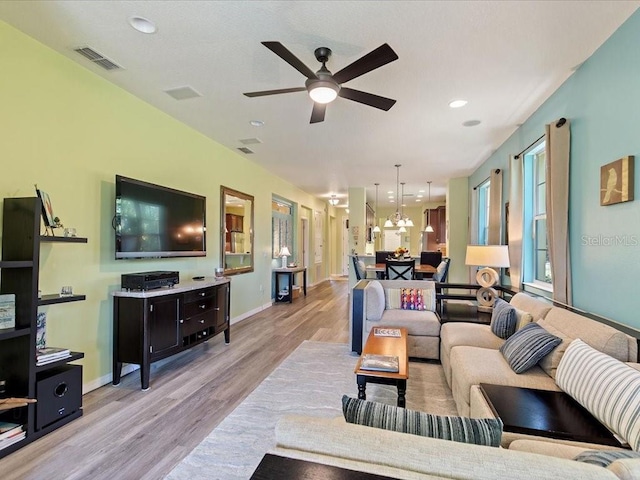 2724 Palm Tree Dr, Poinciana, FL 34759 - living room featuring ceiling fan with notable chandelier, light wood-type flooring, baseboards, visible vents, and recessed lighting