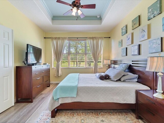 2724 Palm Tree Dr, Poinciana, FL 34759 - bedroom featuring a tray ceiling, light wood-style floors, crown molding, and a ceiling fan