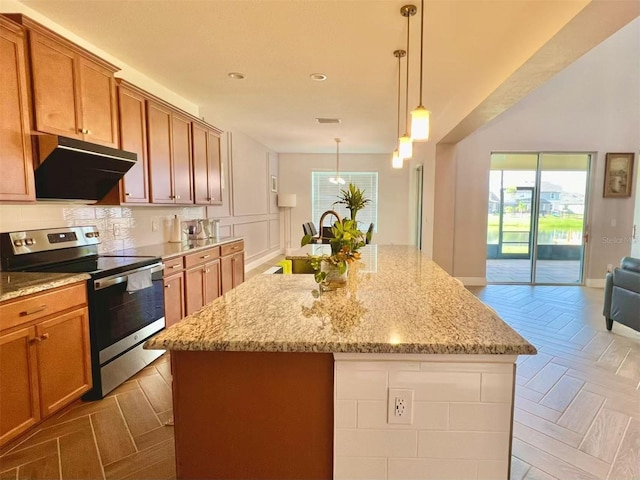 5019 Down Ct, Saint Cloud, FL 34772 - kitchen with under cabinet range hood, light stone countertops, a kitchen island, stainless steel electric range, and open floor plan