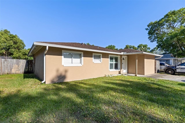view of front of house featuring stucco siding, fence, and a front lawn