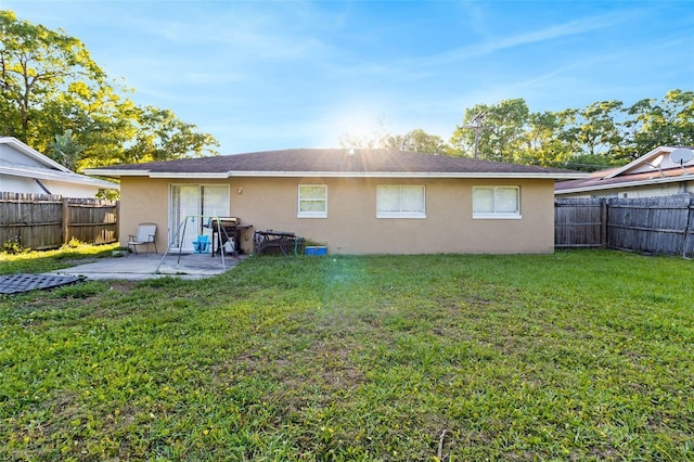 back of house with a yard, stucco siding, a fenced backyard, and a patio area