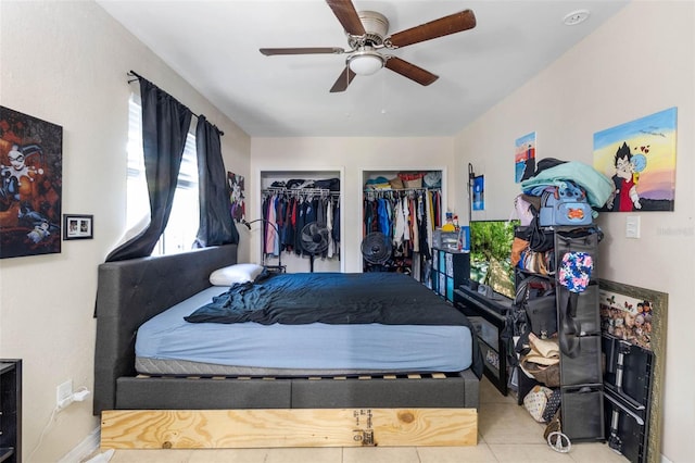 bedroom with tile patterned floors, baseboards, multiple closets, and ceiling fan