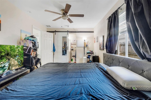 bedroom with ceiling fan, visible vents, and a barn door
