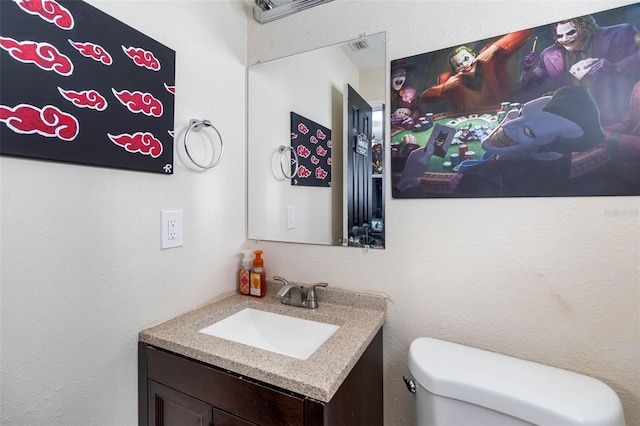 half bath with visible vents, toilet, and vanity