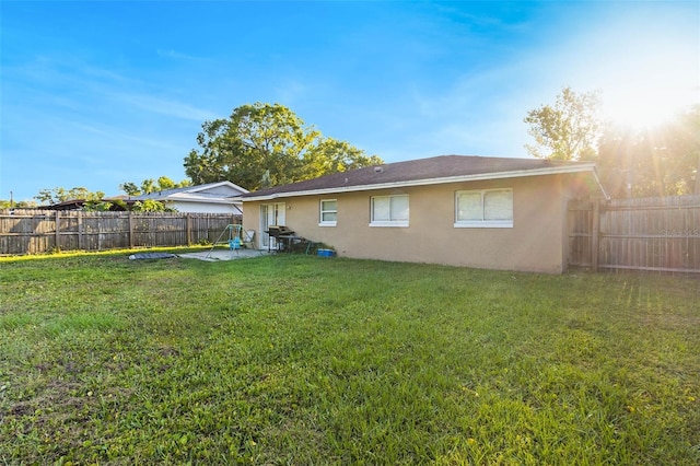 rear view of property with a patio, a fenced backyard, stucco siding, and a lawn