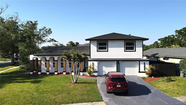 split level home with a front lawn, driveway, fence, and a garage